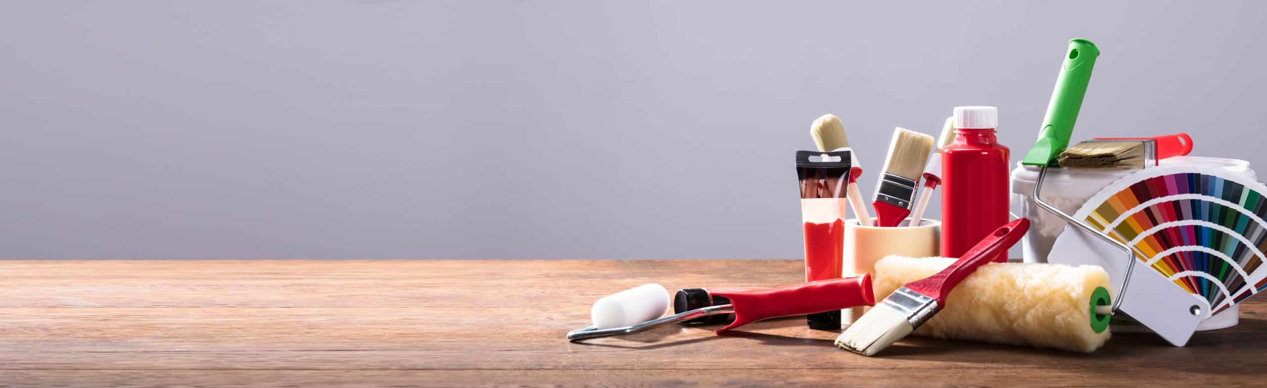 Panoramic View Of Painting Equipments On The Wooden Table Against The Gray Background