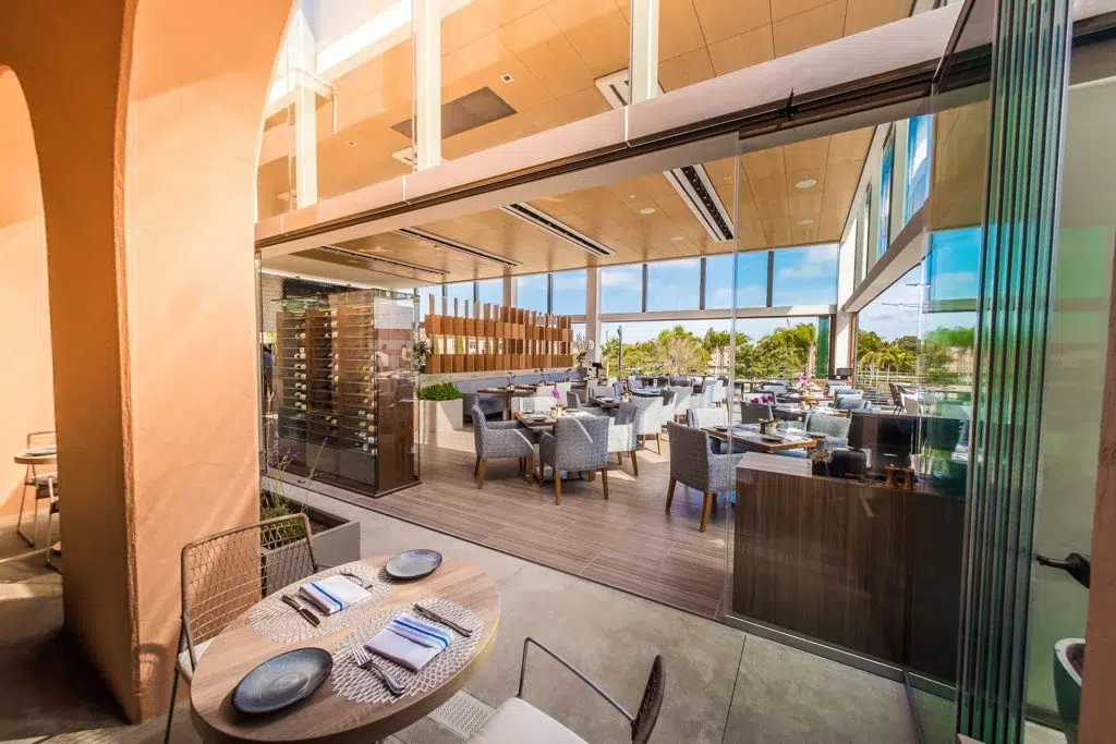 Restaurant with stacked frameless sliding glass doors next to tables.